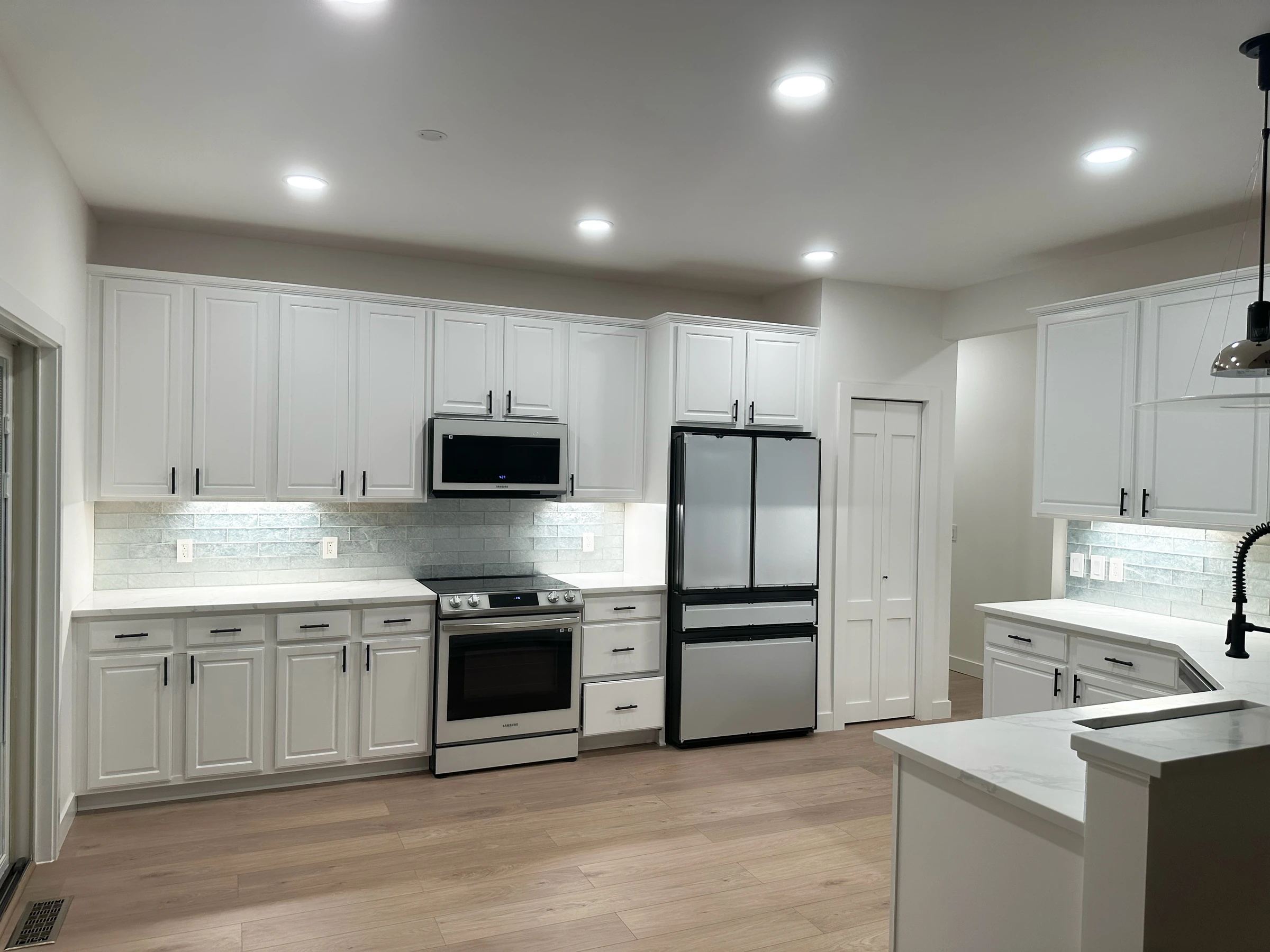 Cozinha moderna em Maple Grove, Minnesota, com armários brancos, backsplash em vidro e eletrodomésticos em aço inox — remodelação VPObras