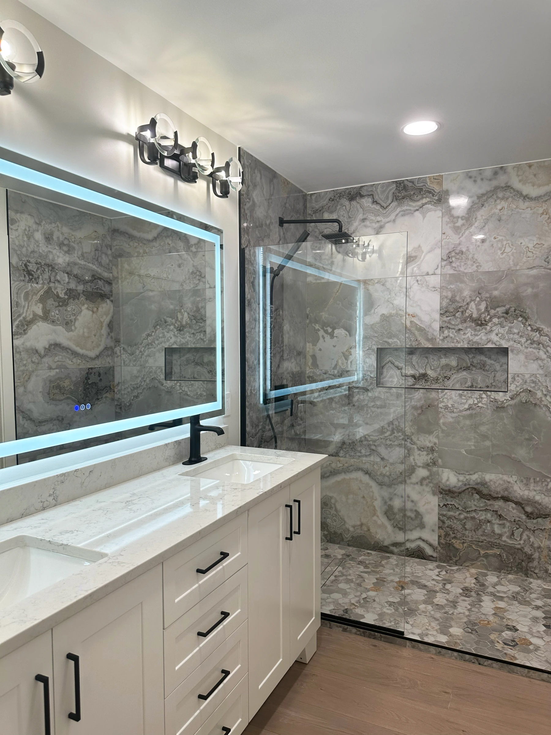Casa de banho moderna em Maple Grove, Minnesota, com duche walk-in, revestimento cerâmico efeito pedra e espelho retroiluminado LED — remodelação VPObras