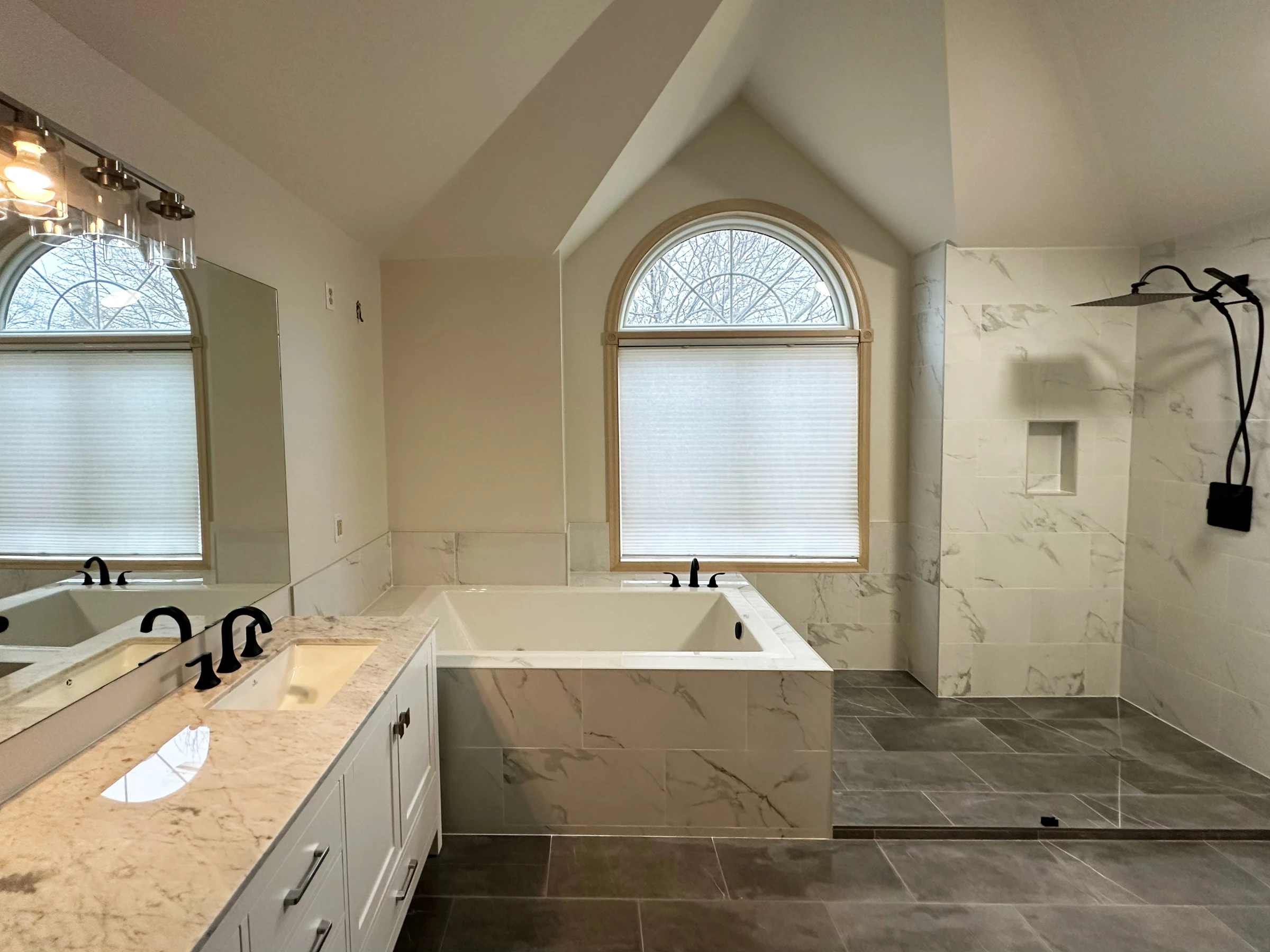 Casa de banho master em Roseville, Minnesota, com banheira jacuzzi embutida junto a janela em arco, revestimento cerâmico efeito mármore e duche walk-in — remodelação VPObras